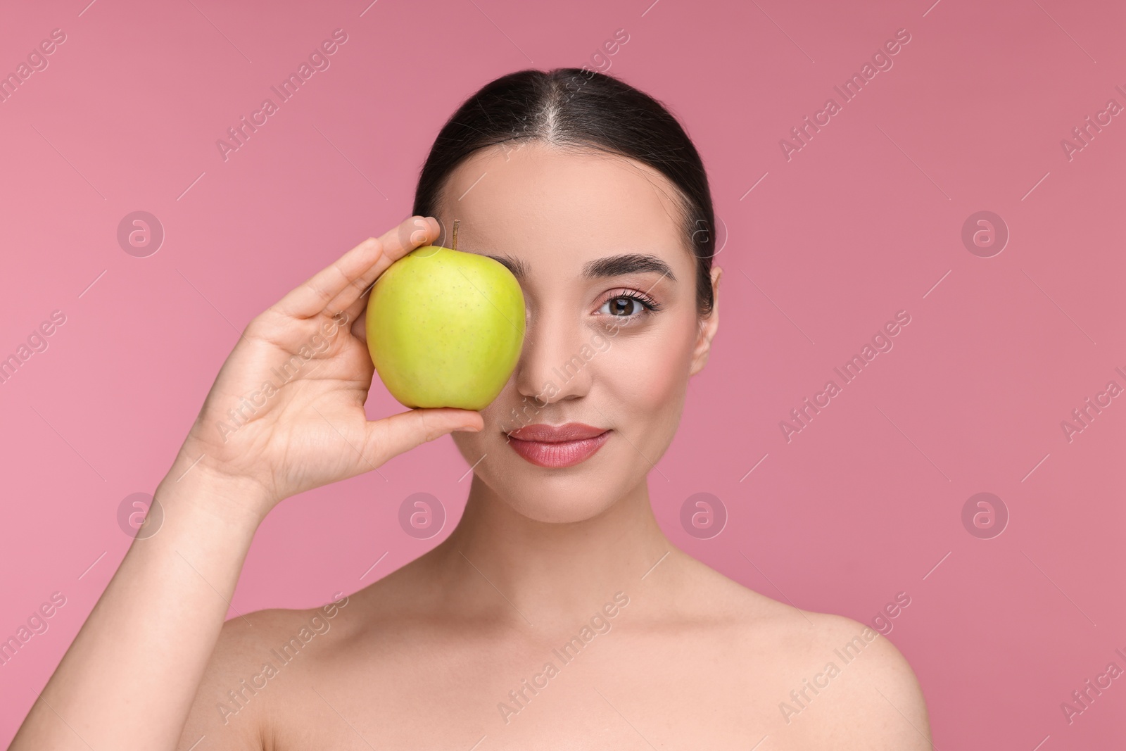 Photo of Beautiful young woman with apple on pink background