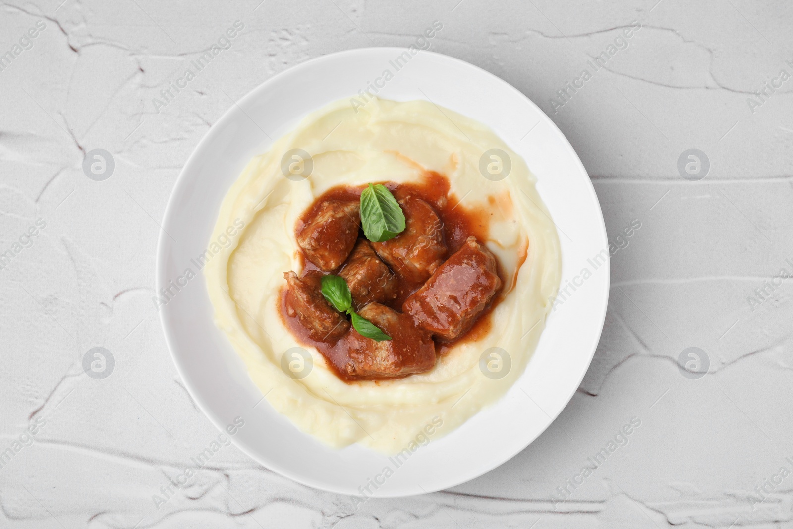 Photo of Delicious goulash with mashed potato on white textured table, top view