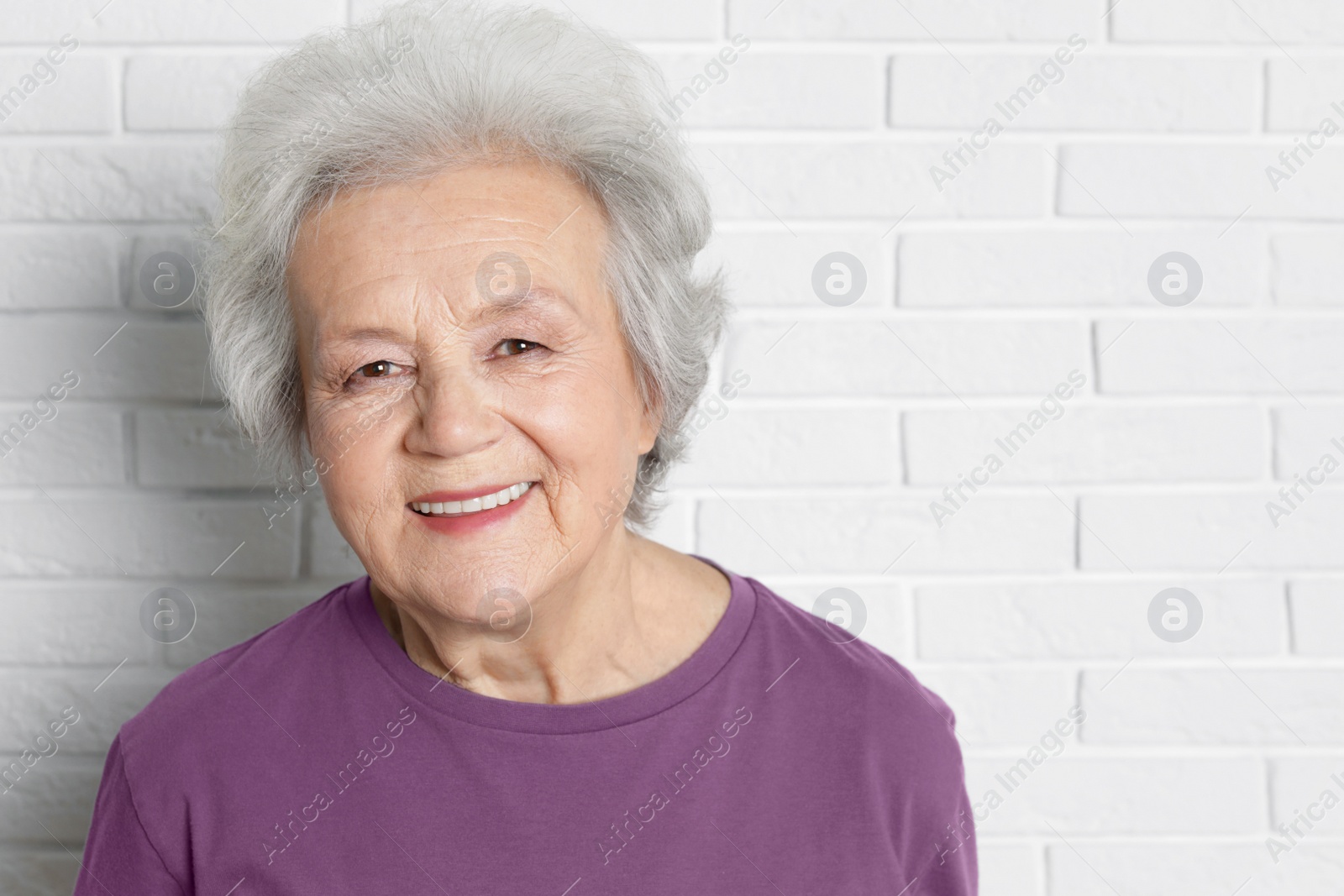 Photo of Portrait of mature woman near brick wall. Space for text