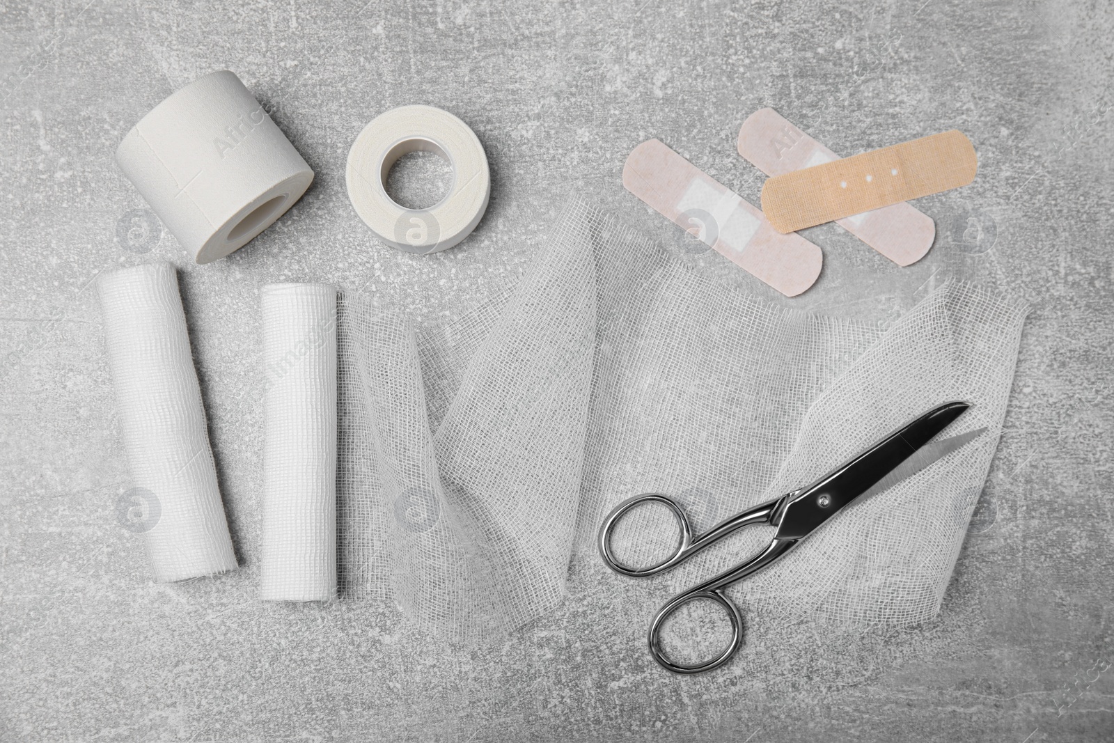 Photo of White bandage rolls and medical supplies on light grey table, flat lay