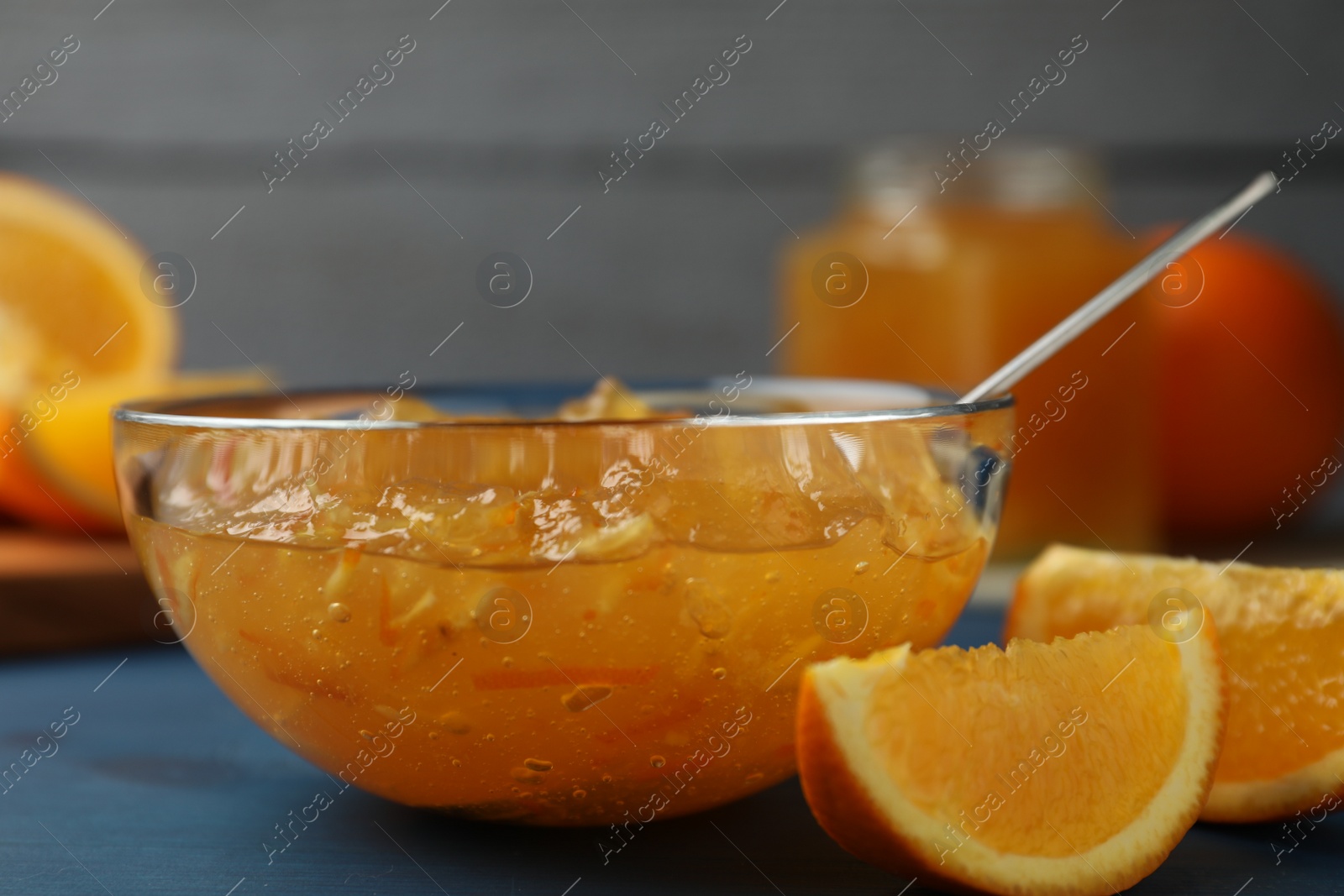 Photo of Delicious orange marmalade in bowl on blue wooden table, closeup