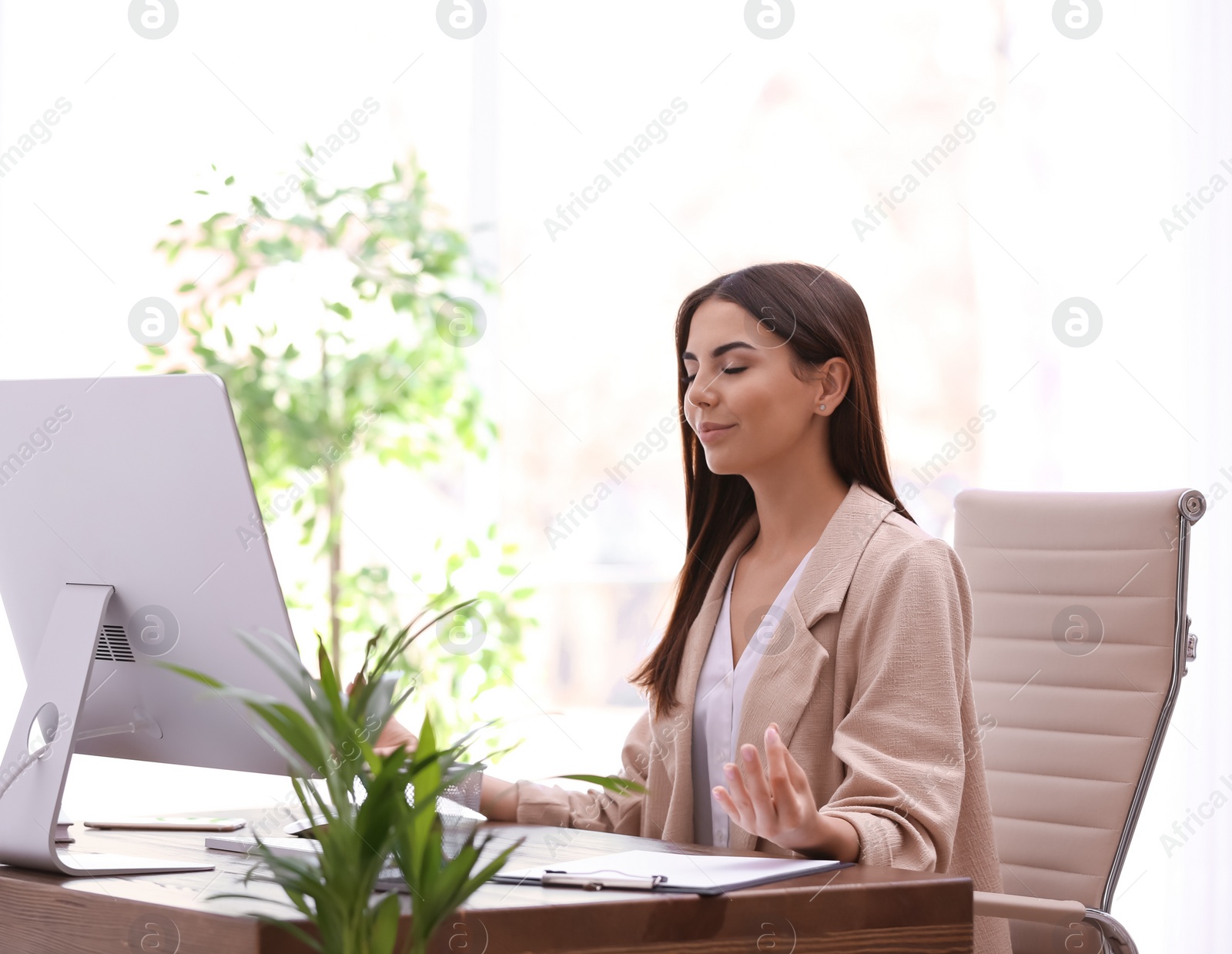 Photo of Young businesswoman meditating at workplace. Zen concept