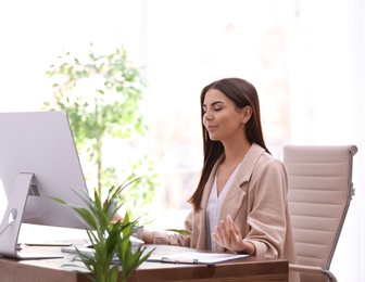 Young businesswoman meditating at workplace. Zen concept