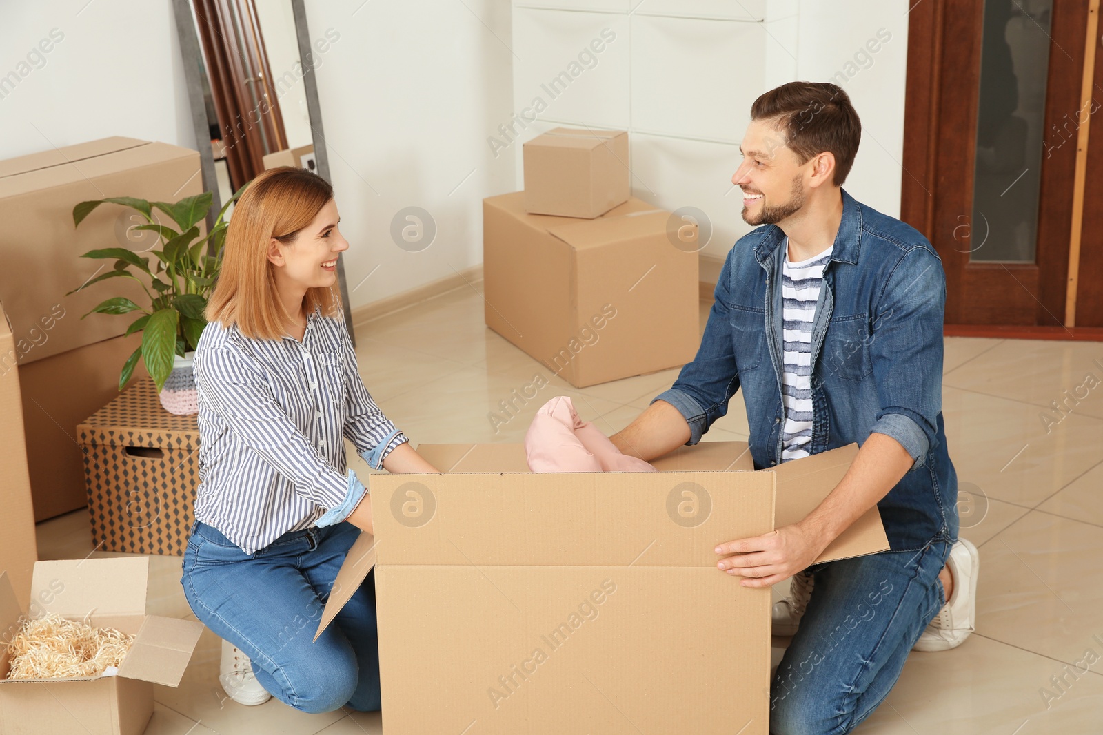 Photo of Happy couple unpacking moving box in their new house