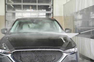 Photo of Cleaning automobile with high pressure water jet at car wash