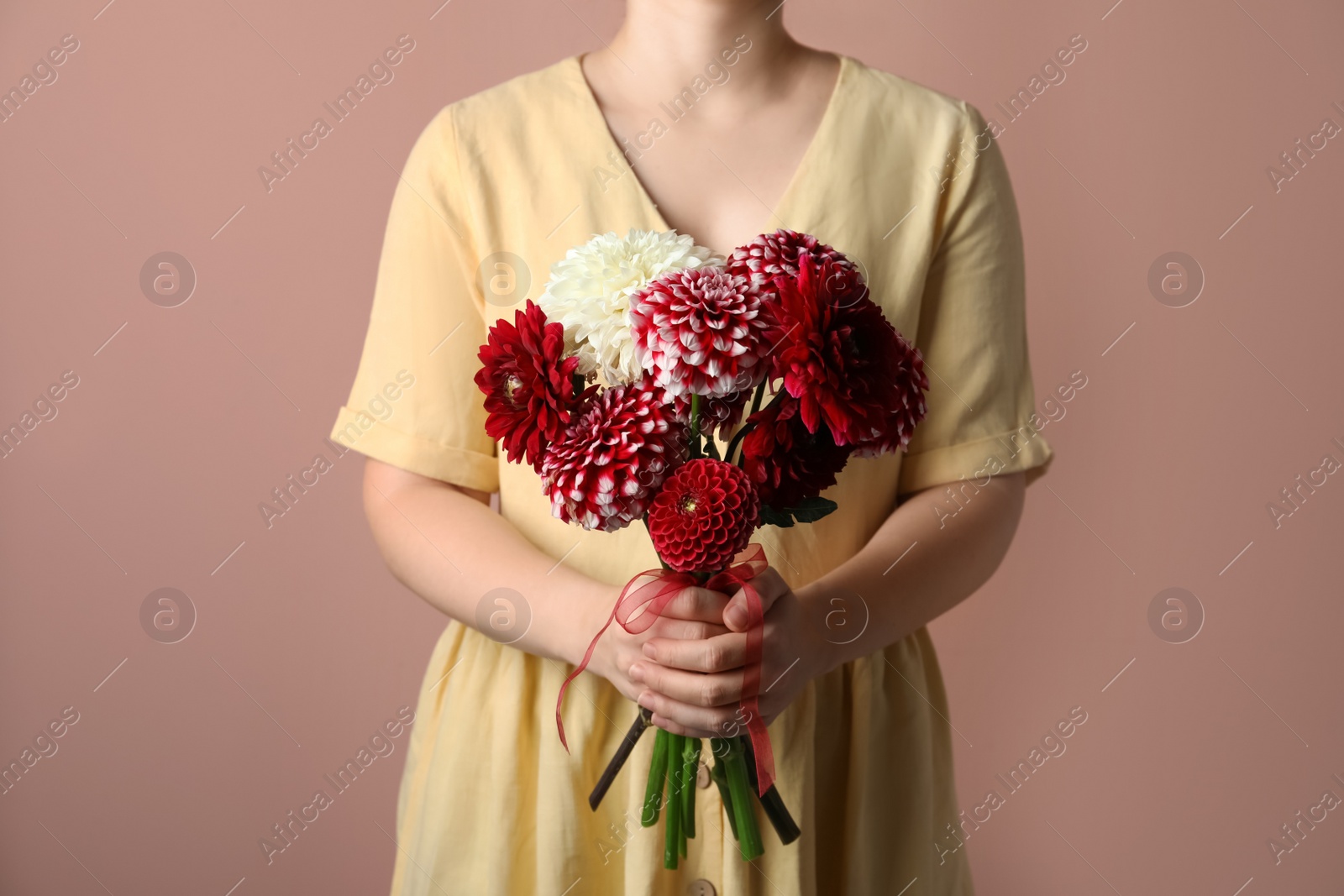 Photo of Woman with bouquet of beautiful dahlia flowers on brown background, closeup