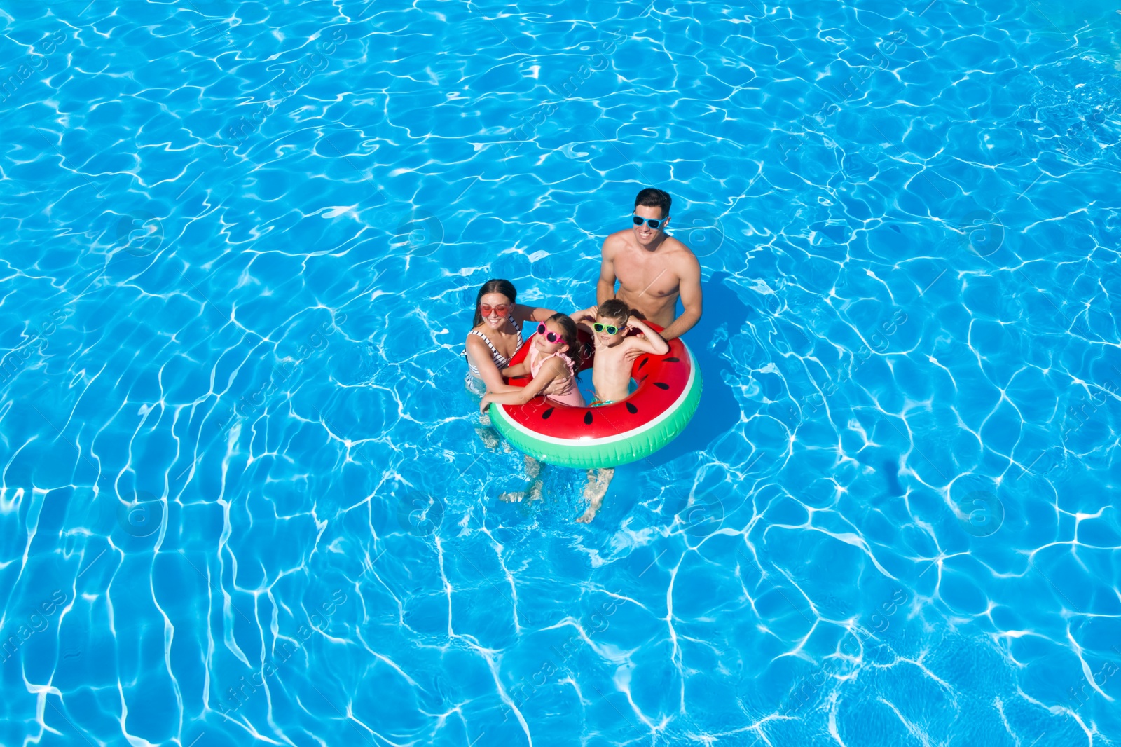 Image of Happy family with inflatable ring in swimming pool. Summer vacation