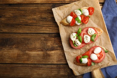 Photo of Delicious sandwiches with mozzarella, fresh tomatoes and basil on wooden table, flat lay. Space for text