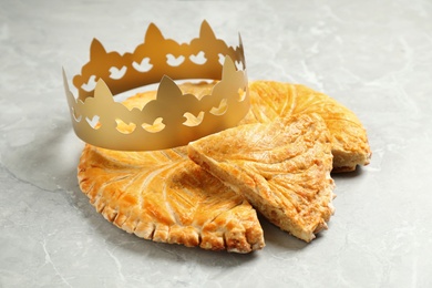 Photo of Traditional galette des Rois with paper crown on light grey marble table