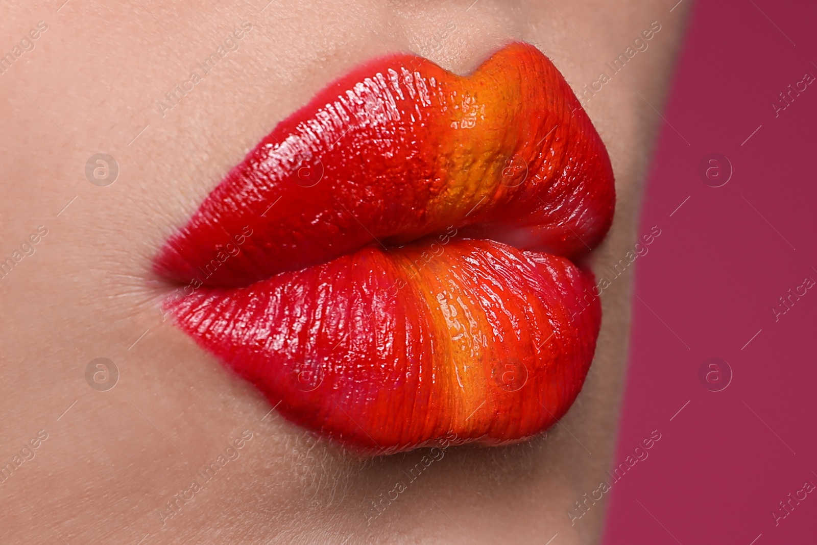 Photo of Young woman with beautiful lips makeup on pink background, closeup