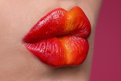 Young woman with beautiful lips makeup on pink background, closeup