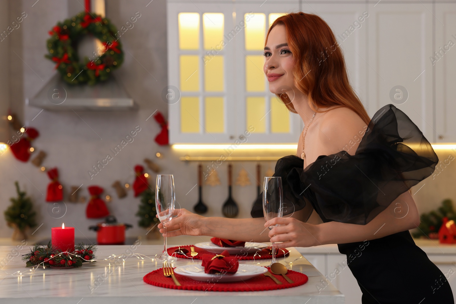 Photo of Beautiful young woman setting table for Christmas celebration in kitchen