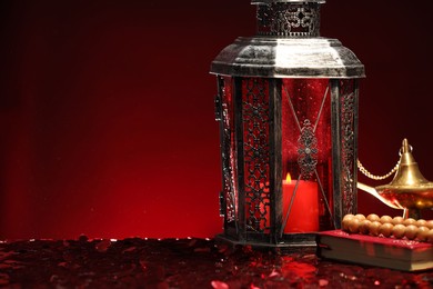 Arabic lantern, Quran, misbaha and Aladdin magic lamp on shiny red table. Space for text