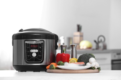 Modern multi cooker and products on table in kitchen