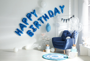 Photo of Phrase HAPPY BIRTHDAY made of blue balloon letters in decorated room