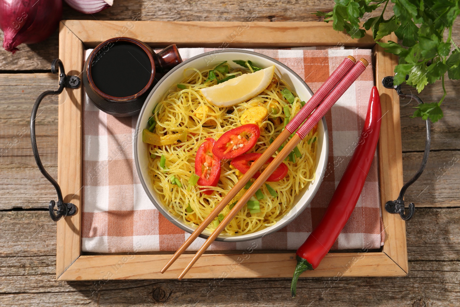 Photo of Stir-fry. Tasty noodles with vegetables and meat in bowl served on wooden table, flat lay