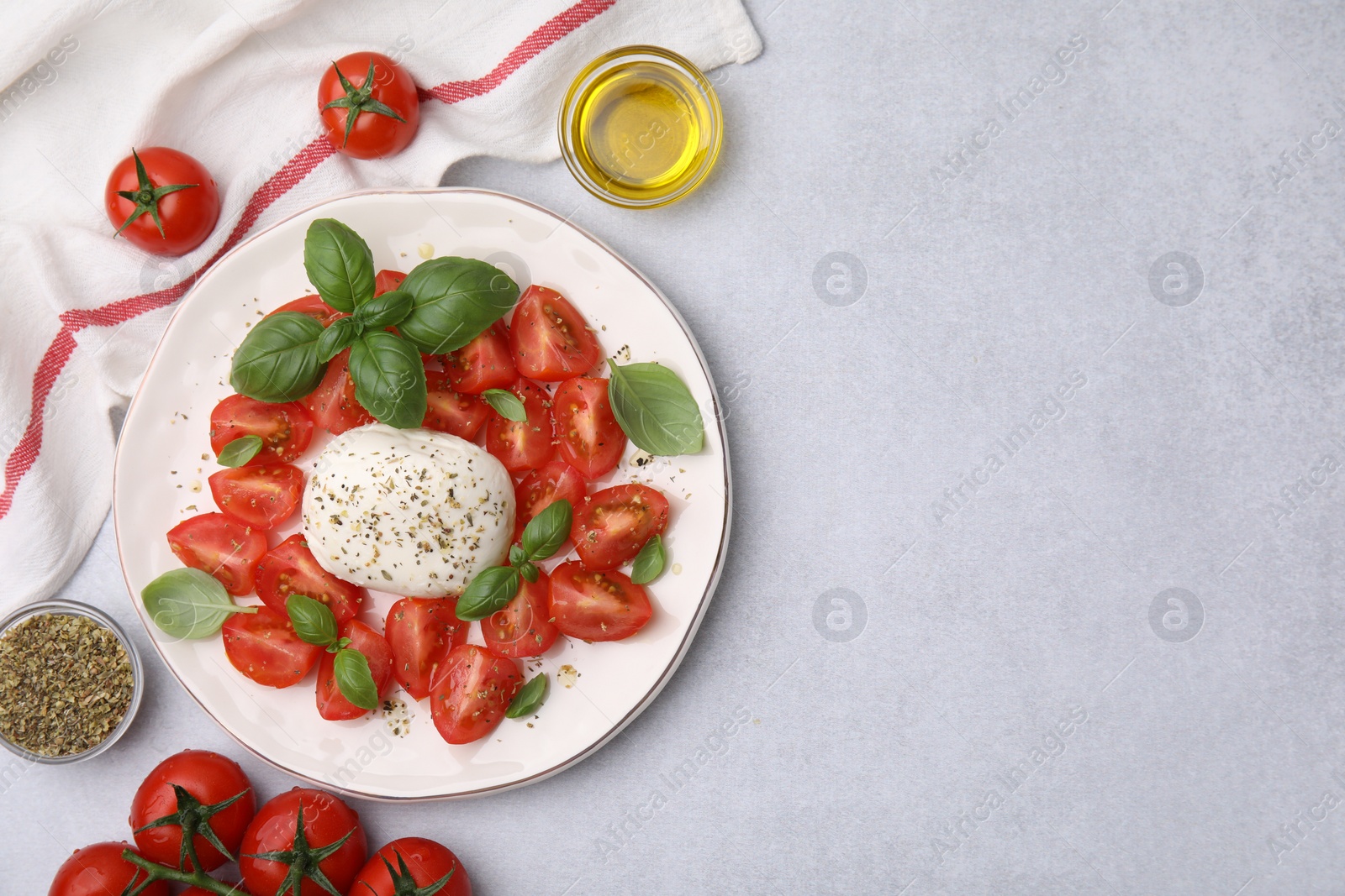 Photo of Tasty salad Caprese with mozarella, tomatoes, basil and other ingredients on light table, flat lay. Space for text