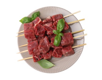 Wooden skewers with cut fresh beef meat, basil leaves and spices isolated on white, top view
