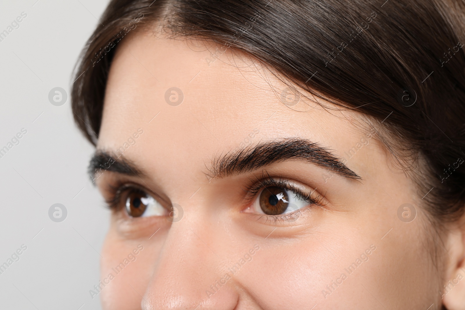 Photo of Woman after eyebrow tinting procedure on grey background, closeup