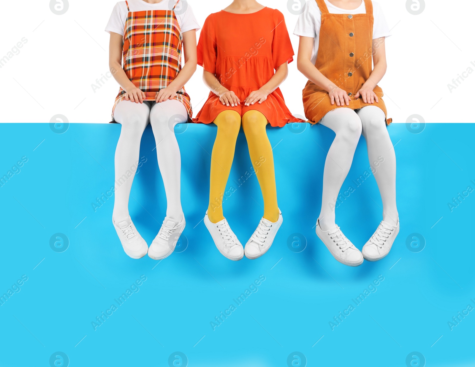 Photo of Group of women wearing colorful tights and stylish shoes sitting on color background, closeup