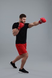 Photo of Man in boxing gloves fighting on grey background