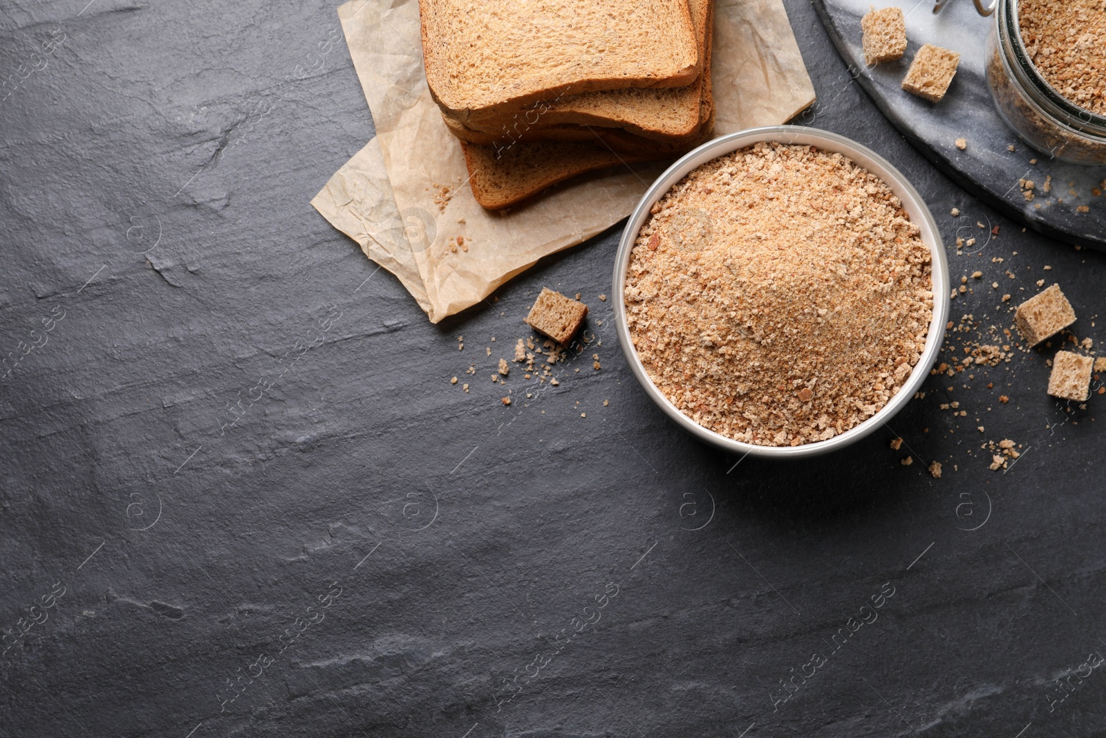 Photo of Fresh breadcrumbs on black table, flat lay. Space for text