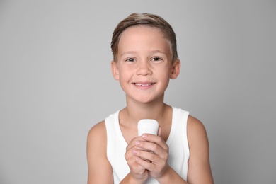 Cute little boy with soap bar on gray background