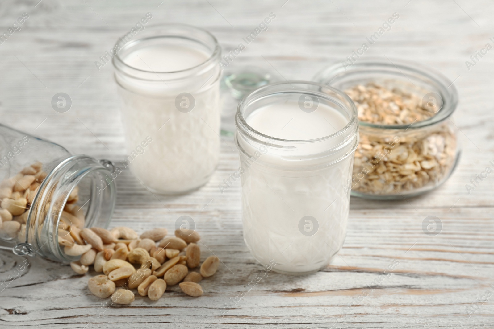 Photo of Jars with peanut and oat milk on wooden background