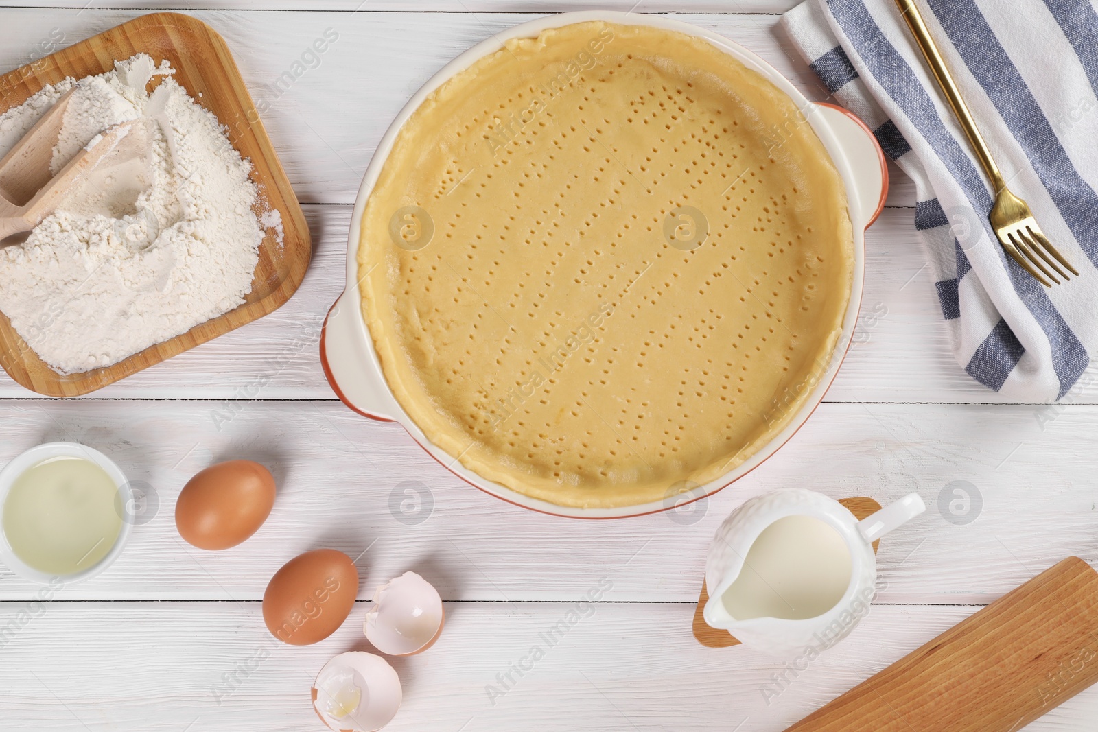 Photo of Pie tin with fresh dough and ingredients on white wooden table, flat lay. Making quiche