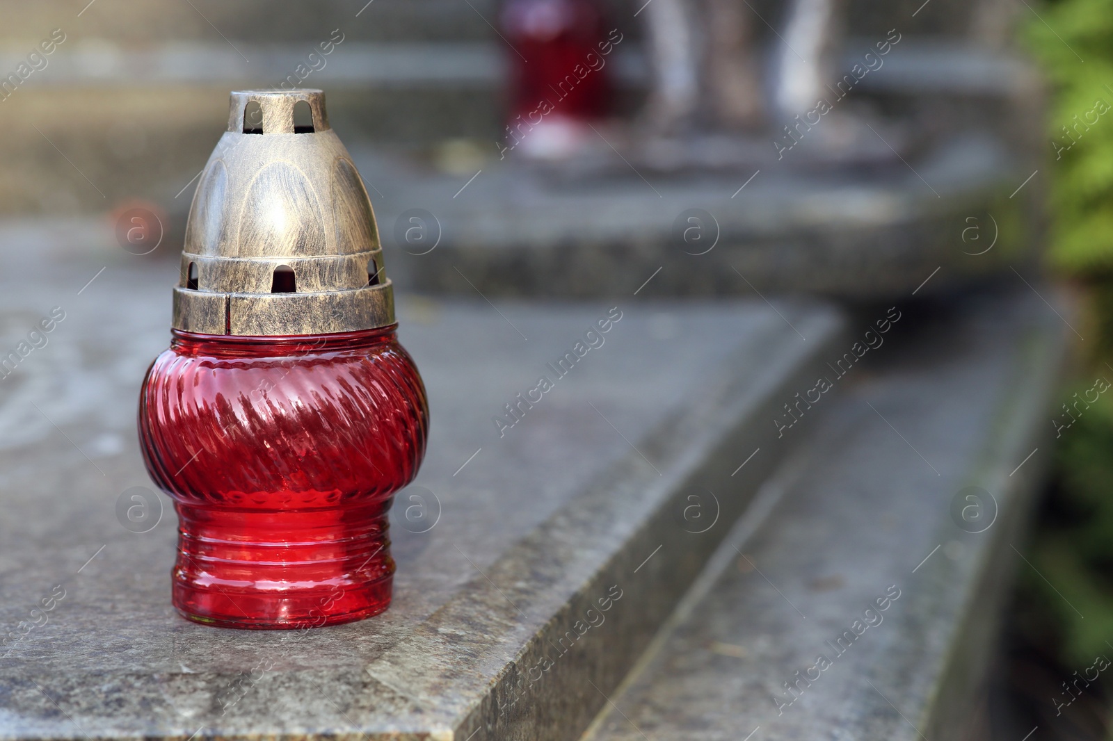 Photo of Red grave lantern with burning candle on granite surface in cemetery, space for text