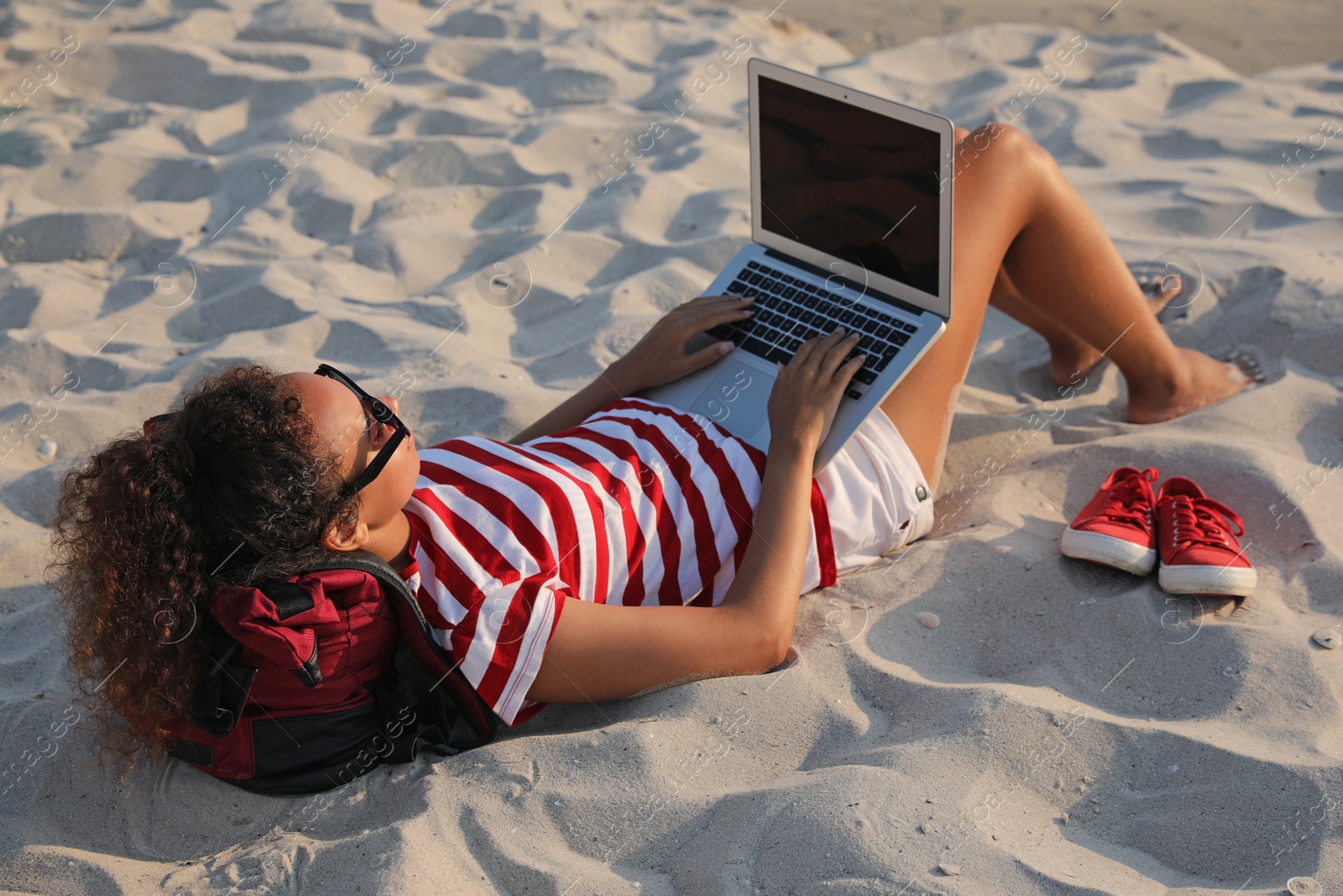 Photo of African American woman working on laptop at beach