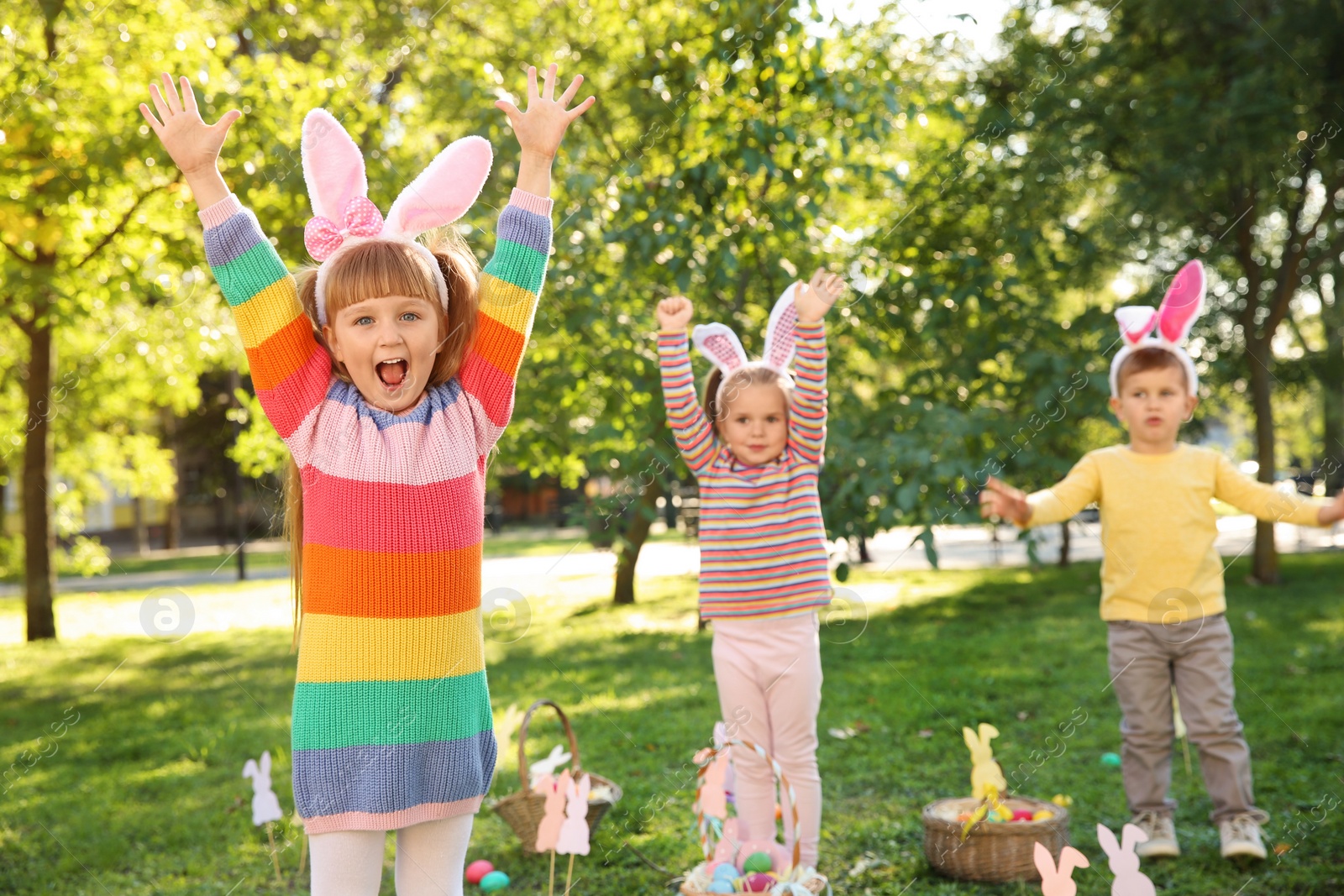 Photo of Cute little children hunting eggs in park. Easter tradition