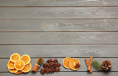 Photo of Flat lay composition with dry orange slices, anise stars and cinnamon sticks on grey wooden table. Space for text