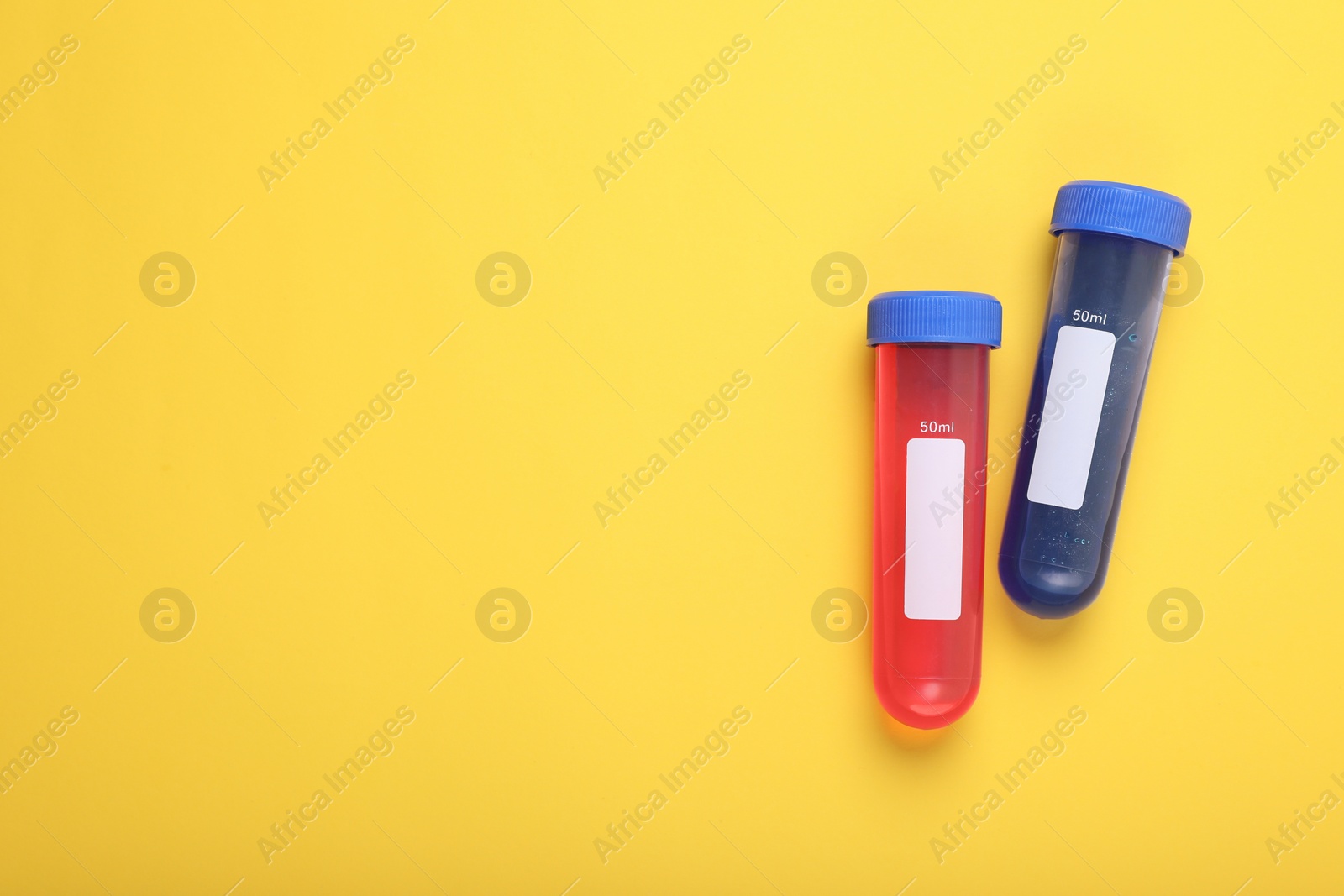 Photo of Test tubes with colorful liquids on yellow background, flat lay and space for text. Kids chemical experiment set