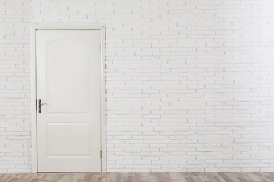 Photo of Closed white wooden door in brick wall