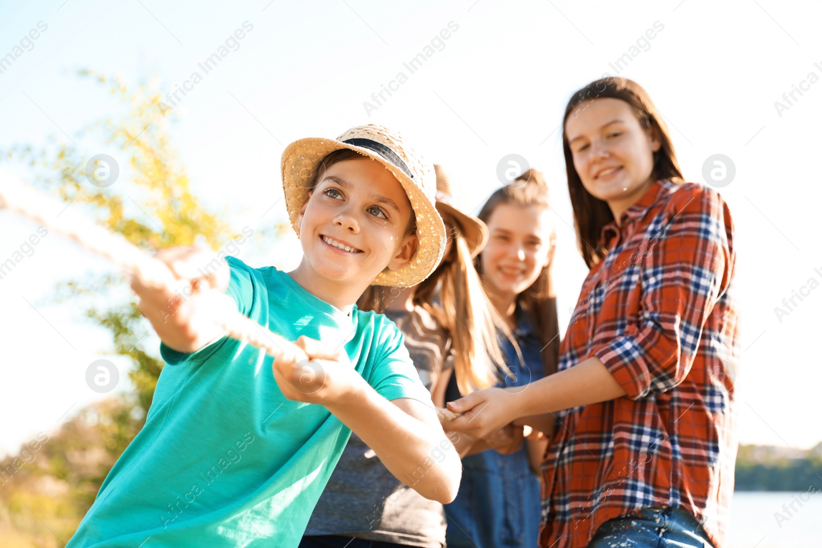 Photo of Group of children pulling rope during tug of war game outdoors. Summer camp