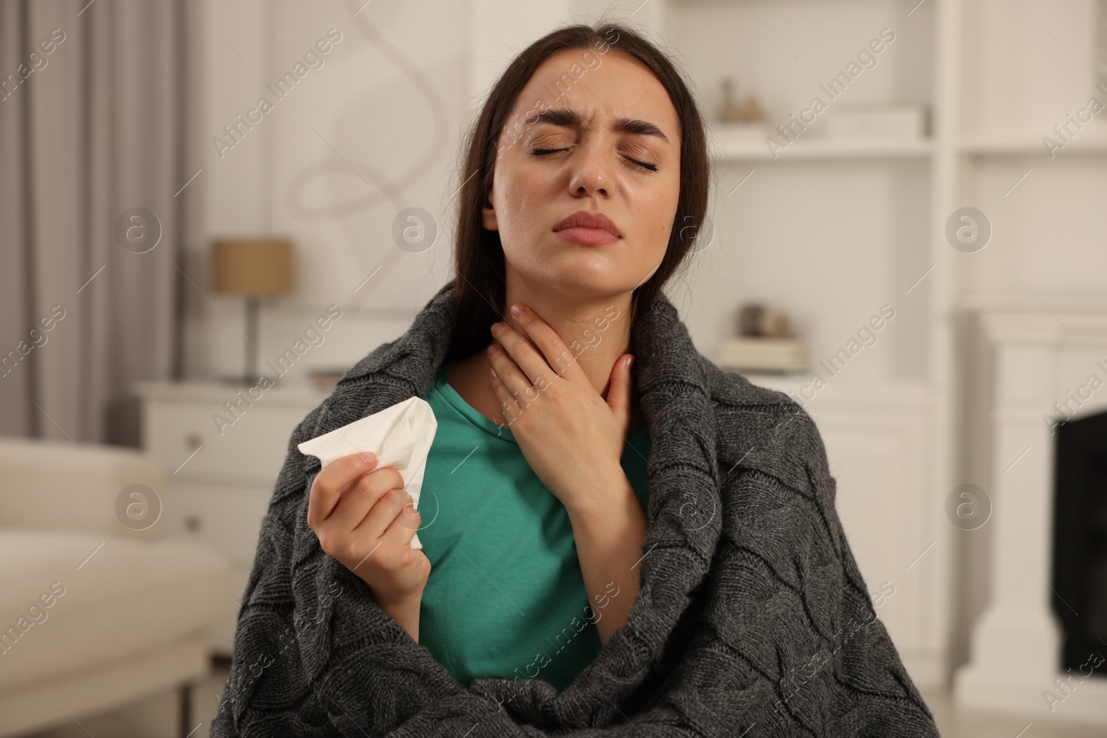 Photo of Sick woman wrapped in blanket with tissue at home. Cold symptoms