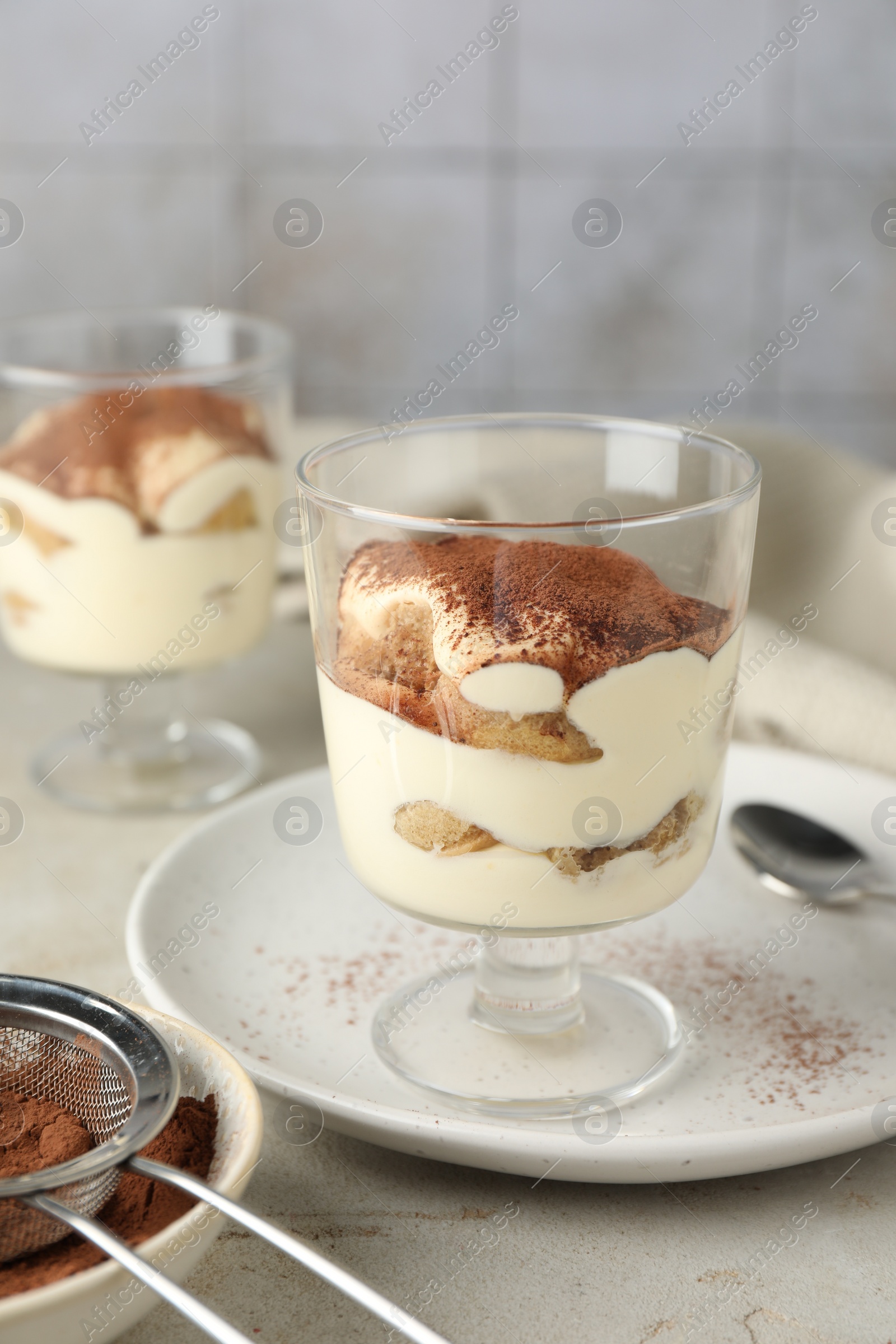 Photo of Delicious tiramisu in glass on light table