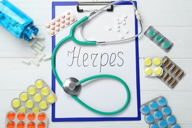 Photo of Clipboard with word Herpes, different pills and stethoscope on white wooden table, flat lay