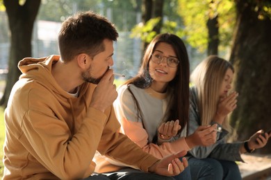 People smoking cigarettes outdoors on sunny day