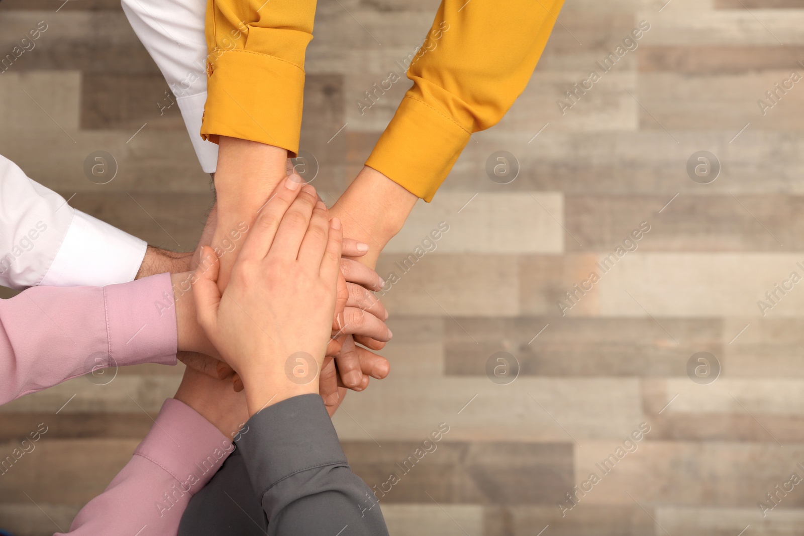 Photo of Young people putting their hands together indoors, top view. Space for text