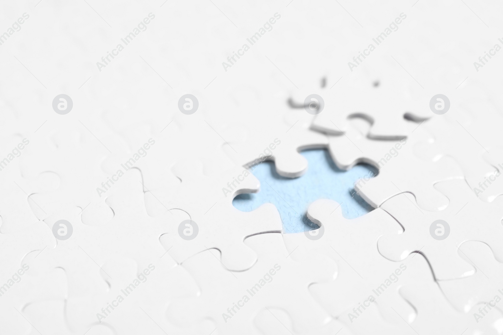 Photo of Blank white puzzle with separated piece on light blue background