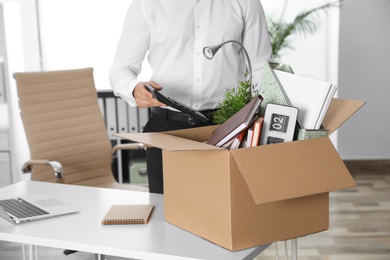 Photo of Young man packing stuff in box at office, closeup