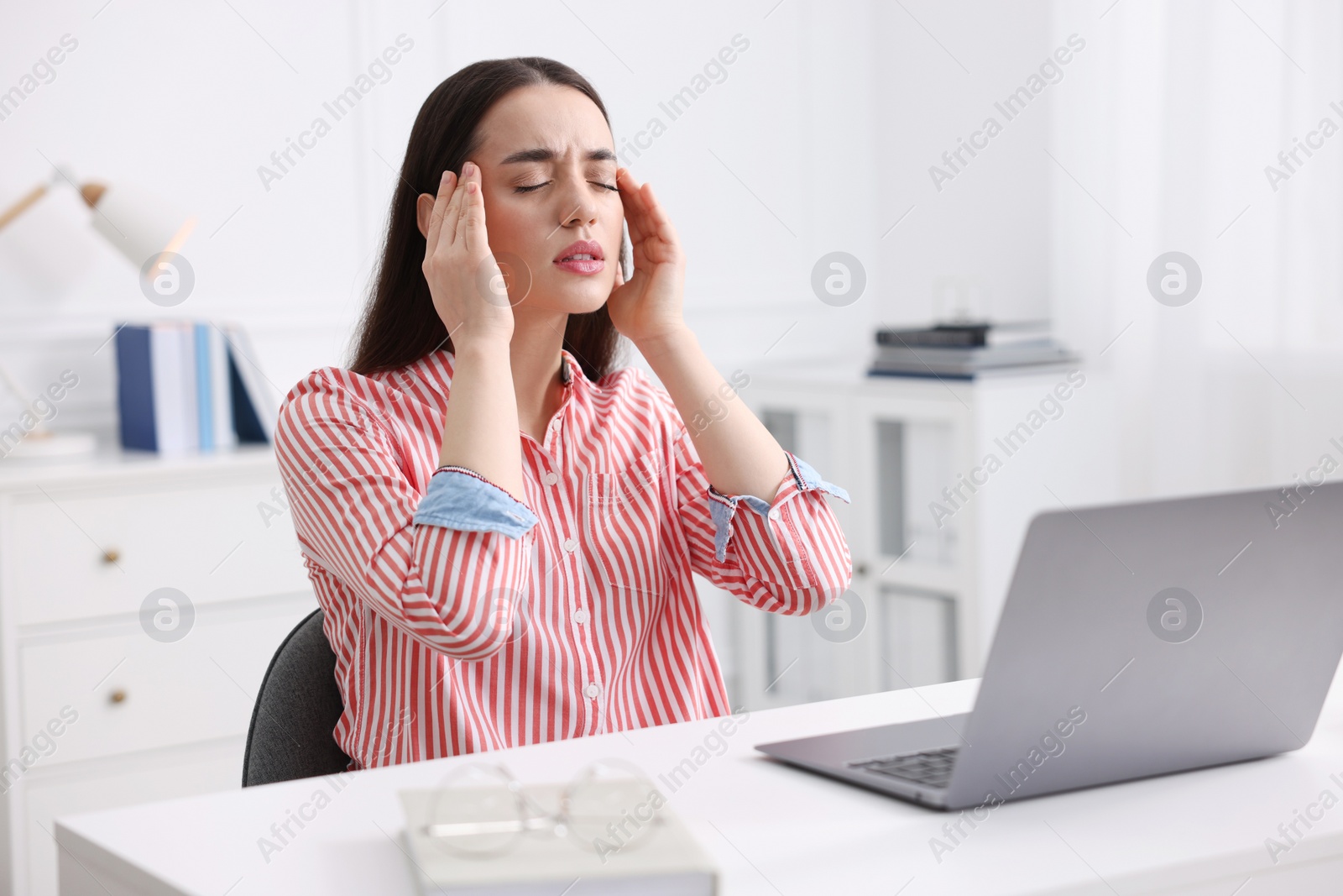 Photo of Woman suffering from headache at workplace in office