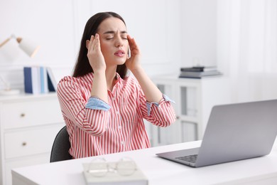 Woman suffering from headache at workplace in office