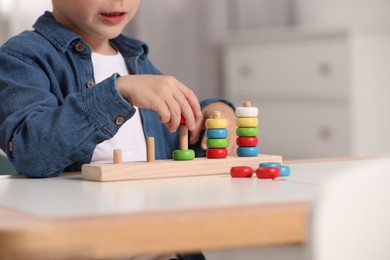 Little boy playing with stacking and counting game at table indoors, closeup. Child's toy