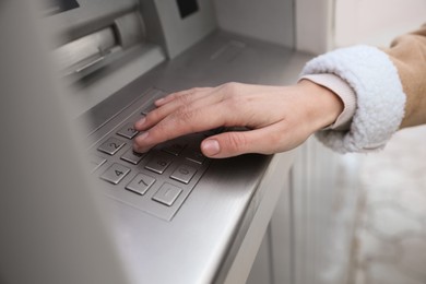 Woman entering cash machine pin code outdoors, closeup