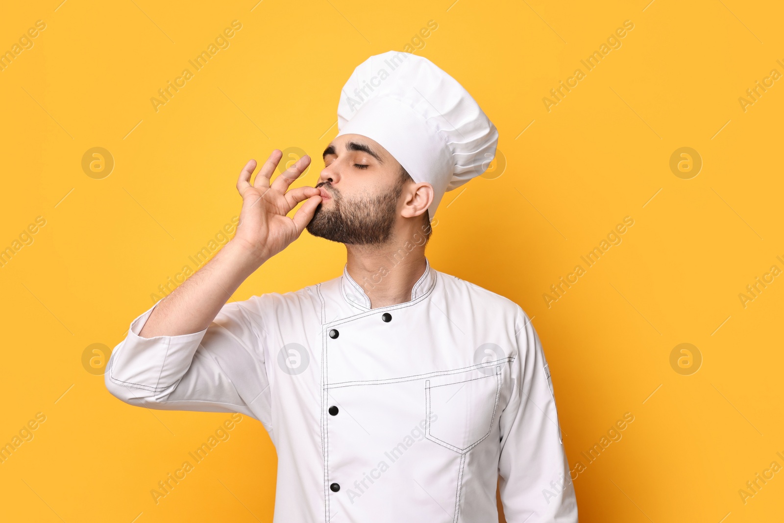 Photo of Professional chef showing perfect sign on yellow background