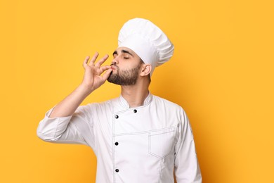 Photo of Professional chef showing perfect sign on yellow background