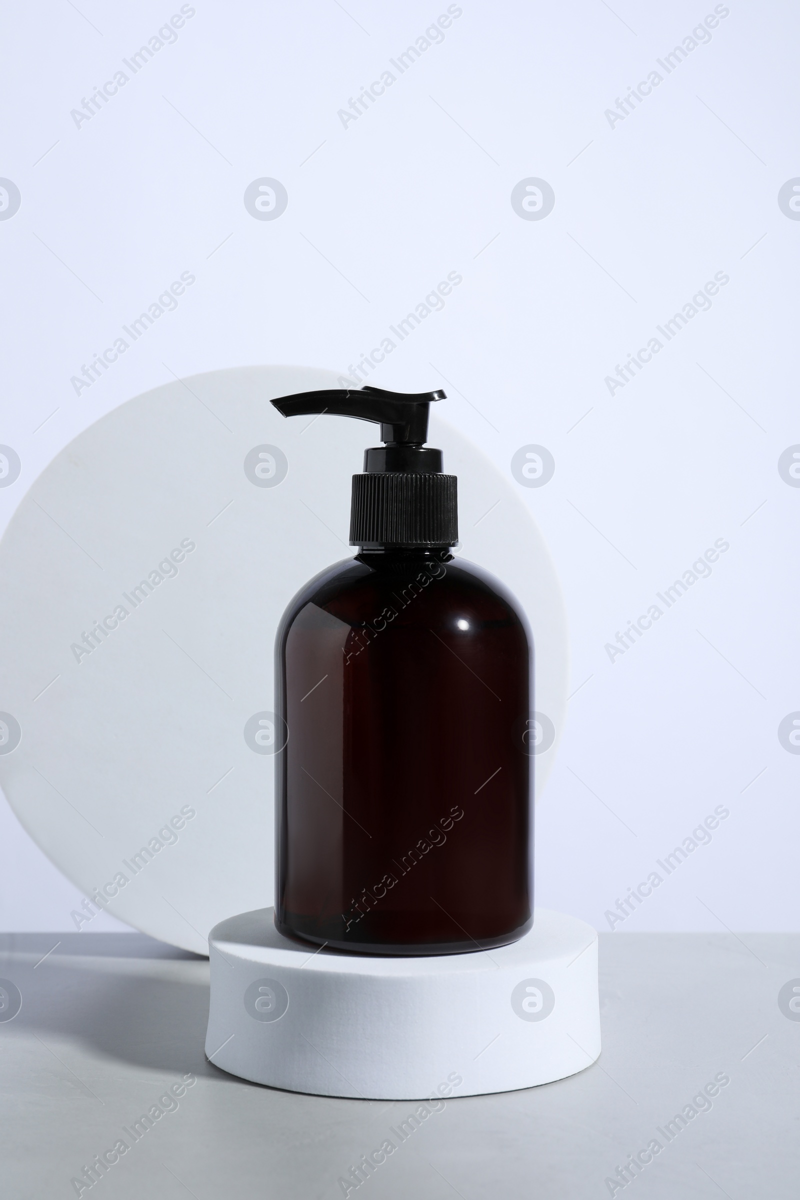 Photo of Bottle of cosmetic product and podiums on light grey table against white background